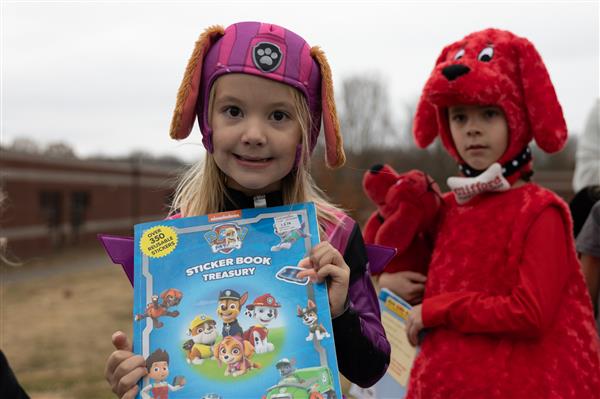 two students smiling outside with a book